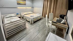 A hotel room with two beds, a desk, a chair, a TV, and a painting on the wall. - The Queen Tropea  (Tropea)