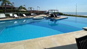 Zona de piscina con sillones de descanso y vista al océano.