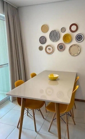 A dining area with a table and chairs, a bowl on the table, and a wall decorated with various plates.