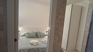 Una camera da letto con un letto, cuscini e un comodino.