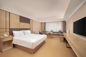 Une chambre d’hôtel moderne équipée d’un grand lit, d’un bureau, d’une chaise, d’une télévision et d’un canapé.