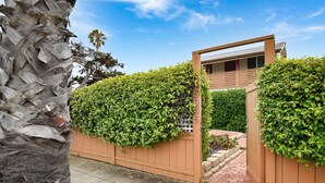 A modern house with a wooden fence and a gate, a paved driveway, and a well-maintained garden.
