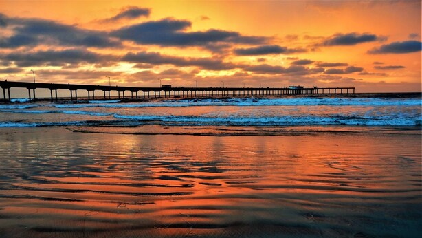 A pier extending into the water with a sunset in the background.