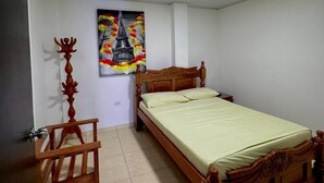 Un dormitorio con cama y silla de madera, un cuadro de una torre y suelo de baldosas.
