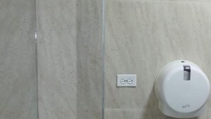 Un baño con un lavamanos blanco, un inodoro y un secamanos fijado a la pared.