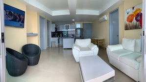 A modern living room with a sofa, armchair, and wicker chairs. A kitchen is visible in the background. - 2P1-32 APARTAMENTO DE 2 ALCOBAS F. MAR (Cartagena)