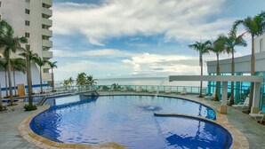 A pool area with a view of the ocean, surrounded by palm trees and lounge chairs. - 2P1-32 APARTAMENTO DE 2 ALCOBAS F. MAR (Cartagena)