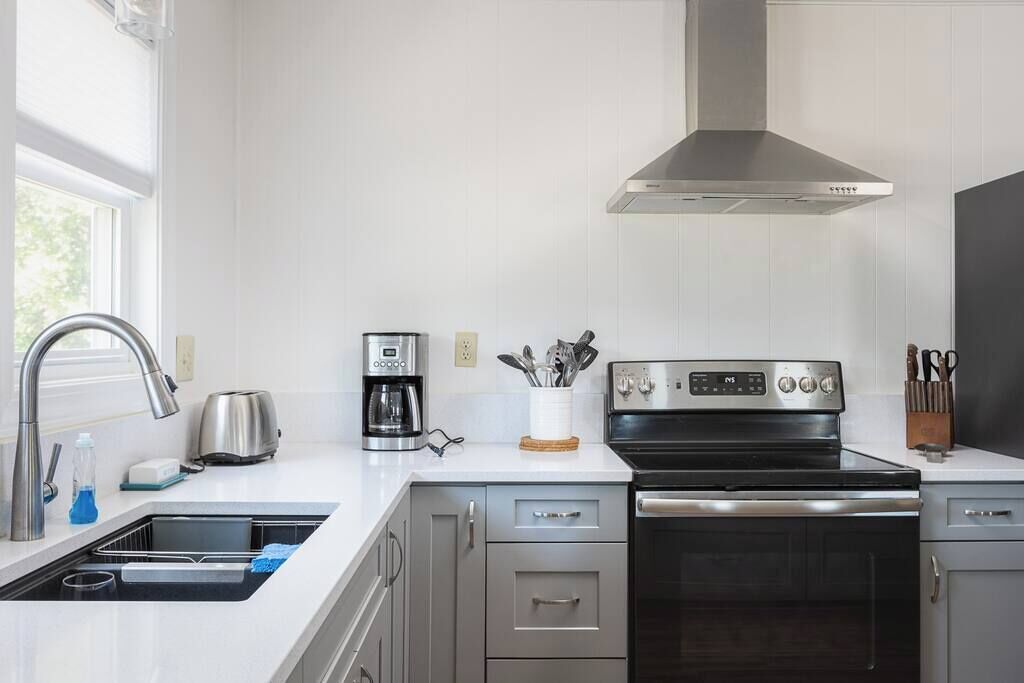 A modern kitchen with a stainless steel range hood, a built-in oven, and a dishwasher.
