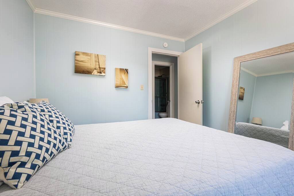 A bedroom with a bed, a door, and a mirror.
