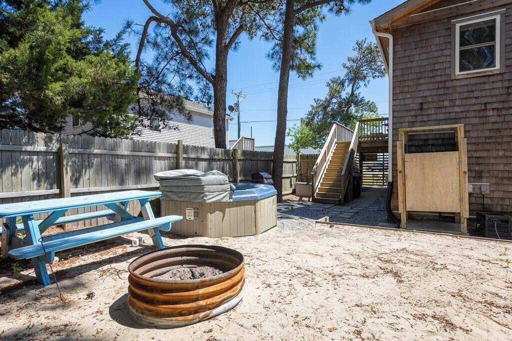 Un jardin avec une terrasse en bois, une table de pique-nique, un jacuzzi et un escalier en bois menant à une autre terrasse.