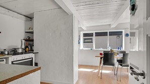 Een moderne keuken met een houten aanrecht, een fornuis en een eethoek met een tafel en stoelen.