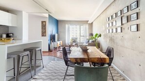 Une cuisine moderne avec un coin bar, une table à manger avec des chaises et un espace salon comprenant un canapé et une plante.