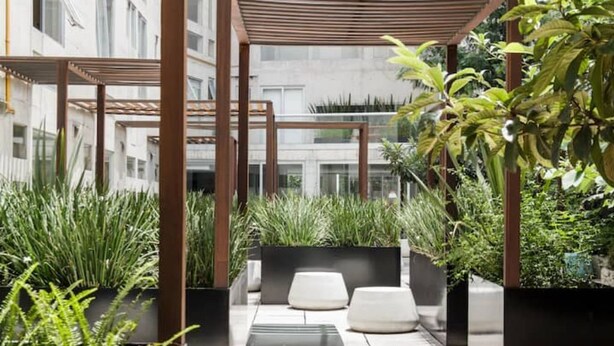 Un jardin sur le toit, agrémenté de jardinières, d’espaces aménagés pour s’asseoir et d’une structure en forme de pergola.
