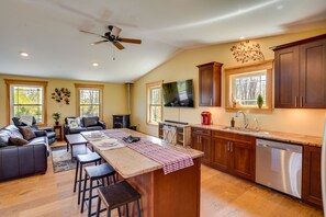 A spacious living area with a large island, dark wooden cabinets, and a modern kitchen with stainless steel appliances.