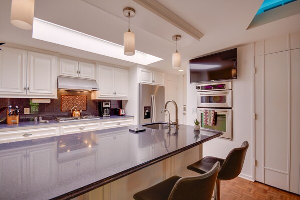 Enjoy cooking and dining in this well-equipped kitchen with a spacious island, appliances, and pendant lighting.