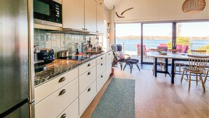 Una cocina moderna con una isla grande, un comedor con vista al agua y una zona de estar acogedora.