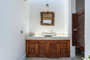 Une salle de bain avec un meuble-lavabo en bois, un lavabo blanc et un miroir au-dessus.