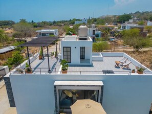 Un toit-terrasse moderne agrémenté d’une pergola, d’un espace salon et de plantes en pot.