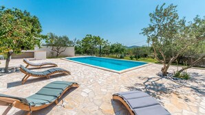 A swimming pool with lounge chairs and stone flooring.
