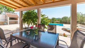 An outdoor patio with a table and chairs, a pool, and a view of the surrounding landscape.