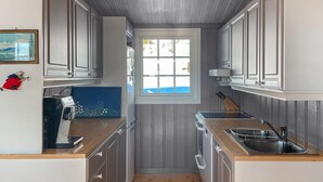 A narrow kitchen with wooden cabinets, a window, and a sink.