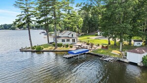 A lakeside house with a dock, a covered boat launch, and a well-maintained lawn.