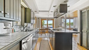 A modern kitchen with a central island, built-in appliances, and large windows offering a view of the outdoors.