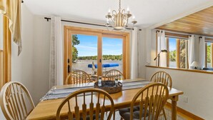 A dining area with a wooden table, chairs, and a view of a lake.