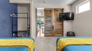 A room with two beds, a TV, a wardrobe, and a hallway leading to a dining area. - Luxe Villa On Golf Course 🏌️~ Private Pool/Spa 🏊 ~EV Charger ~ Tennis (Indio)