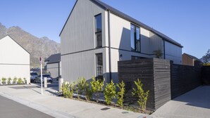 A modern two-story building with a sloped roof, large windows, and a black fence. - Modern 3BR Home, Mountain View, Family Stay, Wi-Fi (Jacks Point)