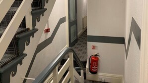 A narrow stairwell with a fire extinguisher mounted on the wall and a door at the end. - Urban Inn (Blackpool)