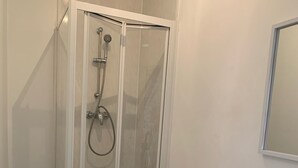 A bathroom with a glass-enclosed shower, a toilet, and a sink with a mirror above it. - Urban Inn (Blackpool)