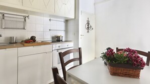 Een keuken met witte kasten, een houten aanrecht, een spoelbak en een eettafel met stoelen.