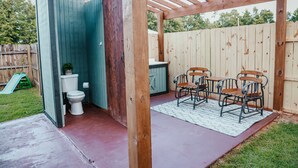 A wooden pergola with a patio area, a toilet, and a small kitchen area with a sink and chairs. - Perfect Family Vacation House (Pace)