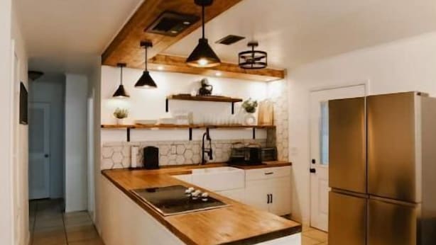A modern kitchen with a central island, pendant lighting, and a stainless steel refrigerator. - Perfect Family Vacation House (Pace)
