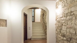 A hallway with a stone wall, a wooden door, and a staircase leading to an upper floor. - S318 - Sirolo, wonderful three-room apartment in a historic building (Sirolo)