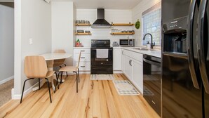 A modern kitchen with white cabinets, a black oven, a microwave, and a refrigerator. - Tourists’ Haven~Clean~Centrally Located (Rapid City)