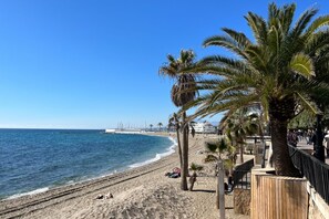 A beach with palm trees, a wooden fence, and a clear blue sky.