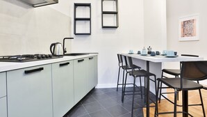 Une cuisine moderne équipée d’une cuisinière à gaz, d’une bouilloire et d’un coin repas avec une table et des chaises.