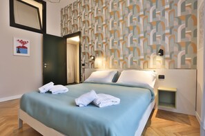 A hotel room with a bed, a nightstand, a wall with a geometric pattern, and a door.