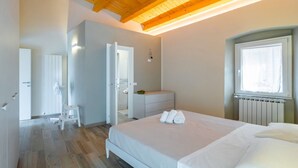 Une chambre à coucher comprenant un lit, une commode, une fenêtre et une porte donnant sur une autre pièce.