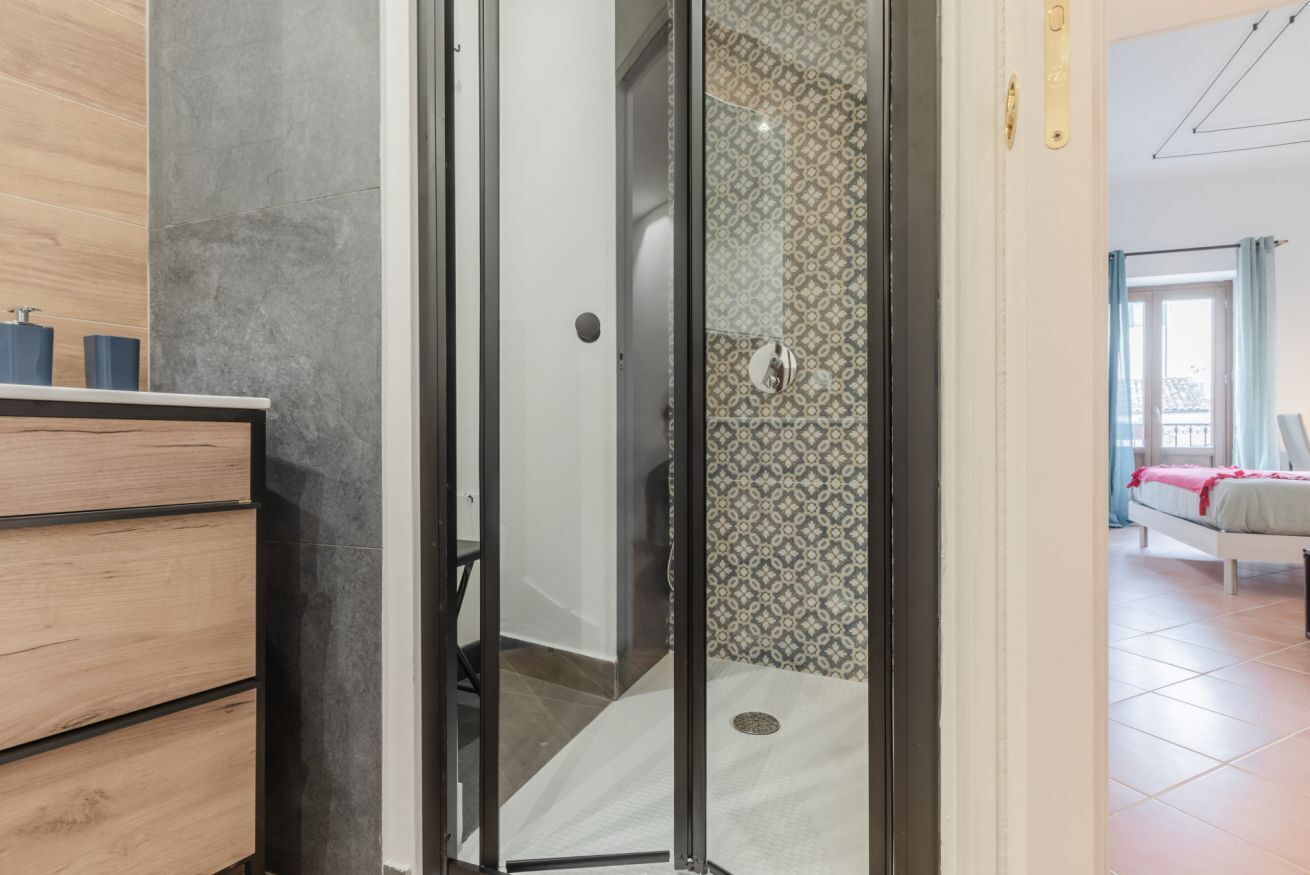 Une salle de bain moderne avec une douche, un meuble-lavabo en bois et un mur orné d’un motif.