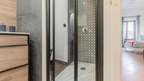 A modern bathroom with a shower, a wooden vanity, and a patterned wall.