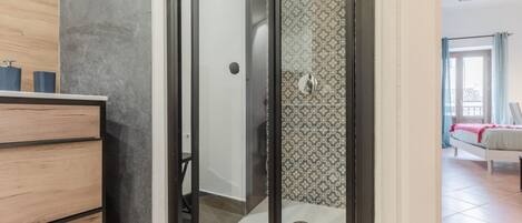 A modern bathroom with a shower, a wooden vanity, and a patterned wall.