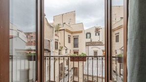A balcony with a wrought iron railing overlooking a residential area with buildings of varying heights and architectural styles.
