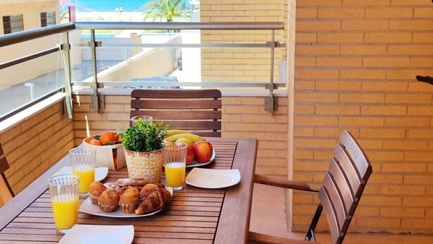Ein Balkon mit Frühstückstisch, komplett mit Croissants, Obst und Saft.
