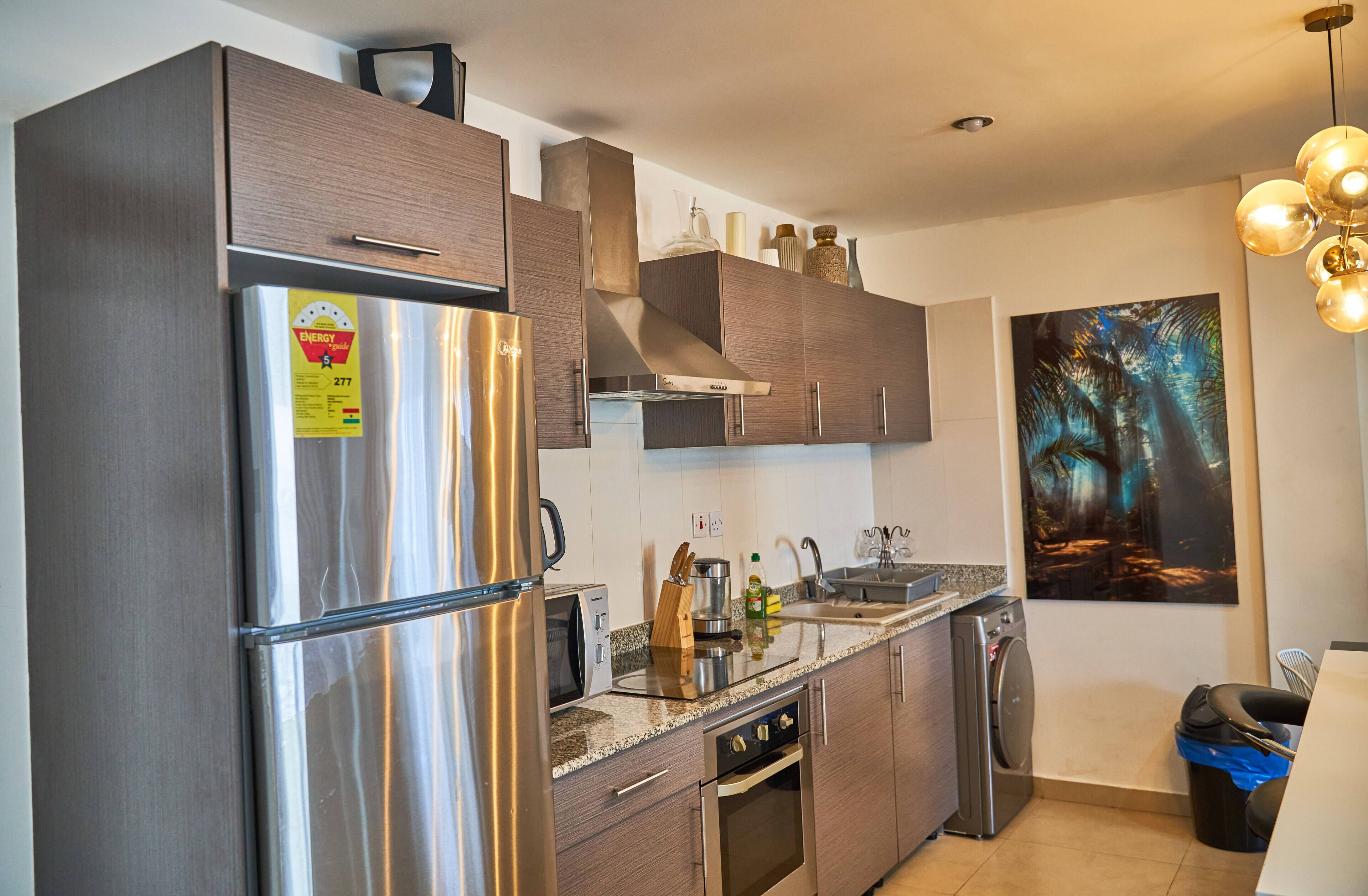 A modern kitchen with stainless steel appliances, wooden cabinets, and a granite countertop.