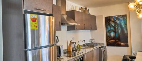 A modern kitchen with stainless steel appliances, wooden cabinets, and a granite countertop.