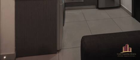 A compact kitchen with a built-in oven, a stainless steel refrigerator, and a microwave.