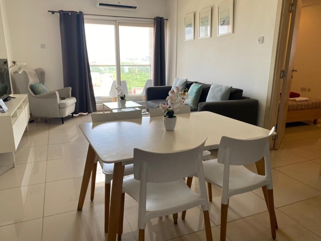 Ein modernes Wohnzimmer mit Esstisch und Stühlen, einer Couch und einem Balkon mit Vorhängen.